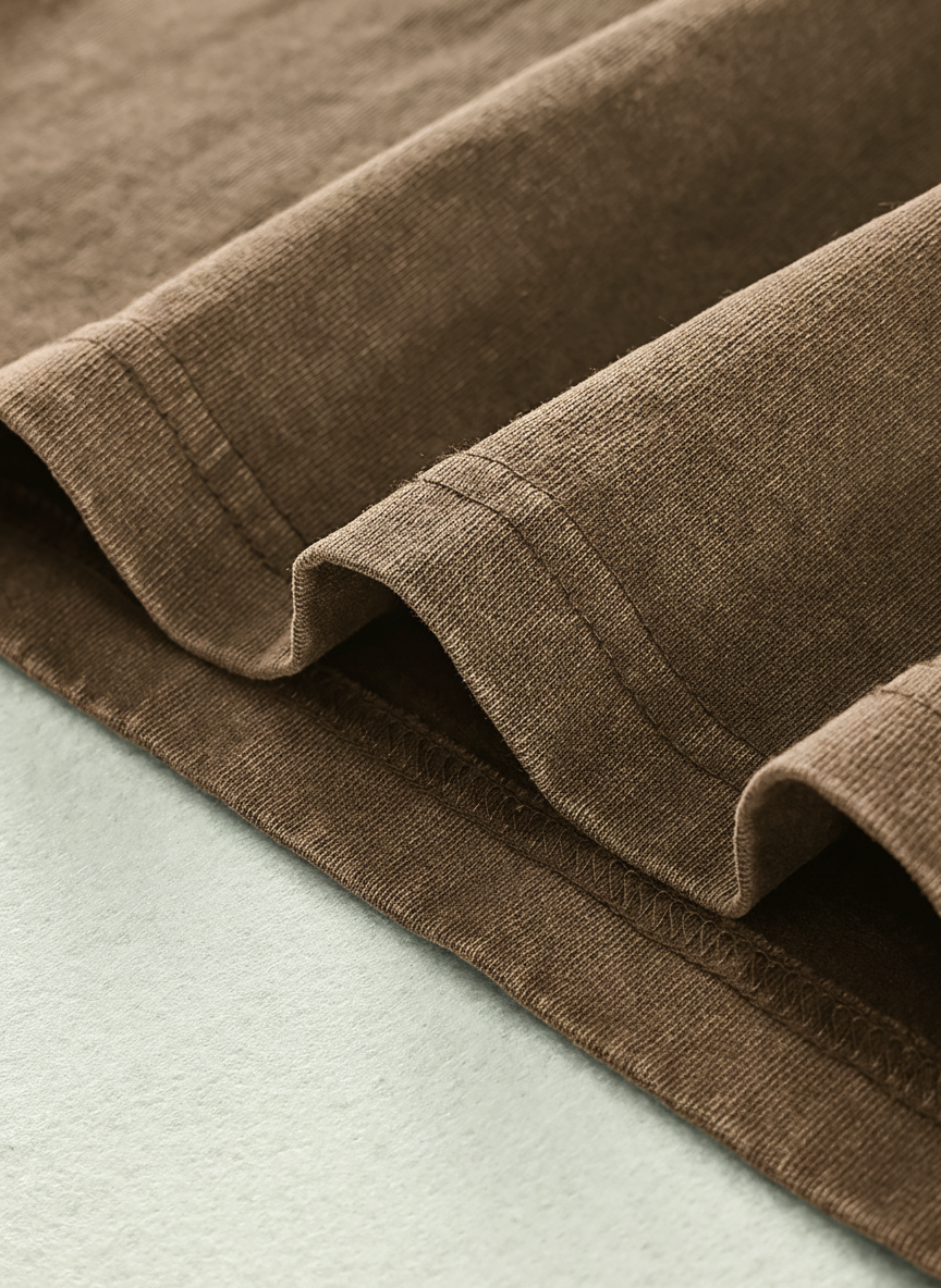 a close-up view of a brown fabric, possibly a piece of clothing or a textile, with a light green background.