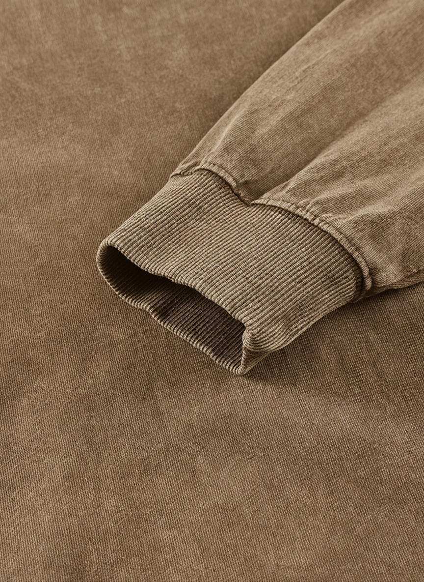 A close-up view of a beige fabric, possibly a sweater or a jacket, with a ribbed texture.