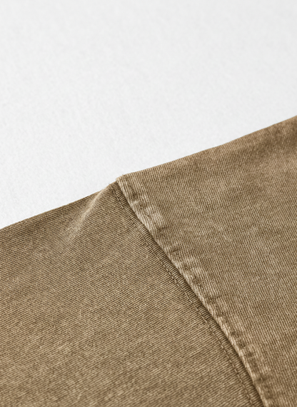 A close-up view of a piece of brown fabric, possibly denim, with a slight crease visible.
