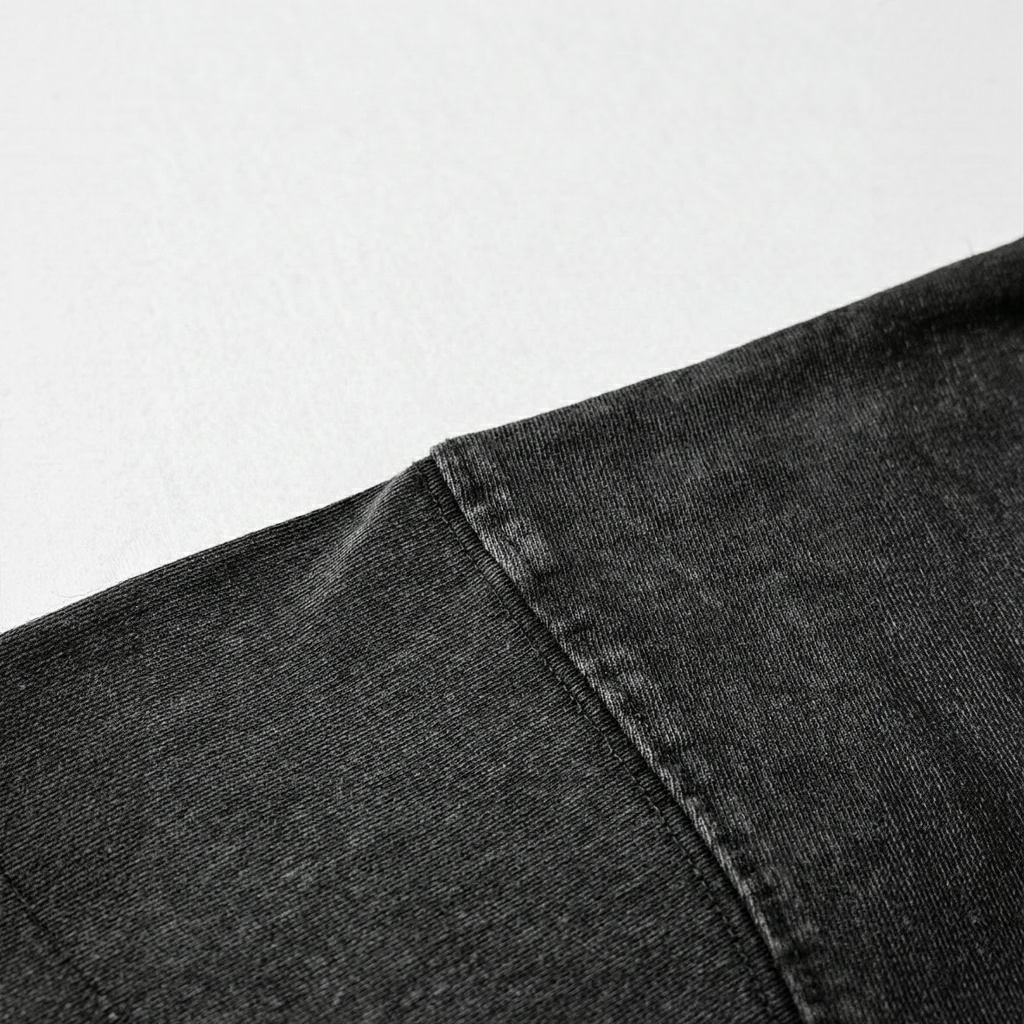 A close-up view of a black fabric, possibly denim, with a noticeable crease or fold in the fabric.