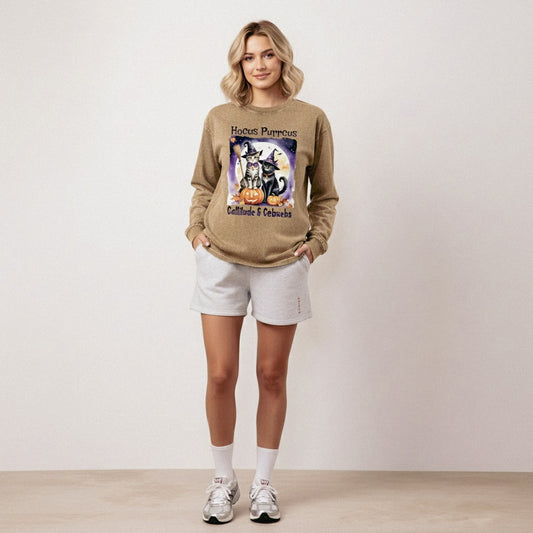 Woman wearing a Halloween-themed sweatshirt with cats and pumpkins on a plain background