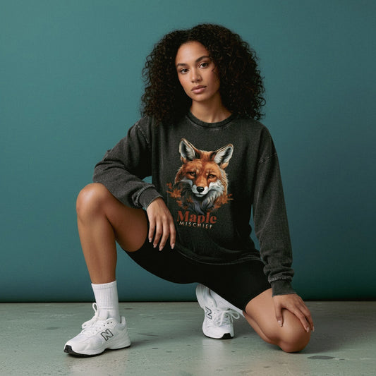 Woman wearing a sweatshirt with a fox design and 'Maple Mischief' text against a teal background