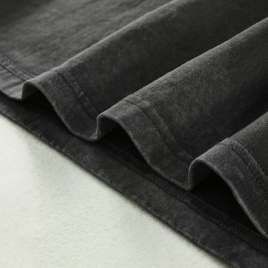 A close-up view of a dark grey fabric, possibly denim, with a folded or rolled edge.