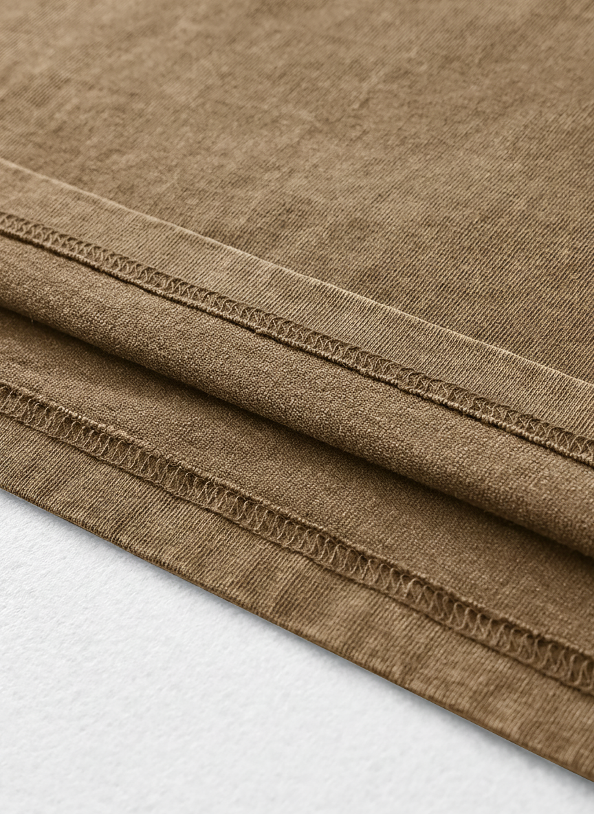 a close-up view of a brown fabric, possibly a piece of clothing or a textile. The fabric appears to be folded or rolled, with visible stitching or seams running across it.