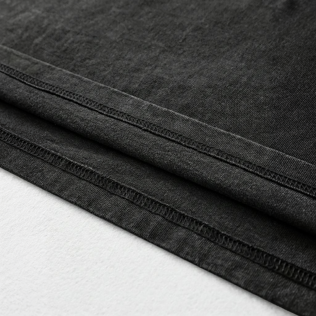A close-up view of a black fabric, possibly denim, with visible stitching and folds.