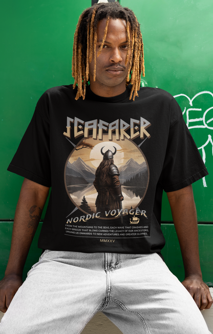 Person wearing a black t-shirt with a graphic design sitting against a green wall.